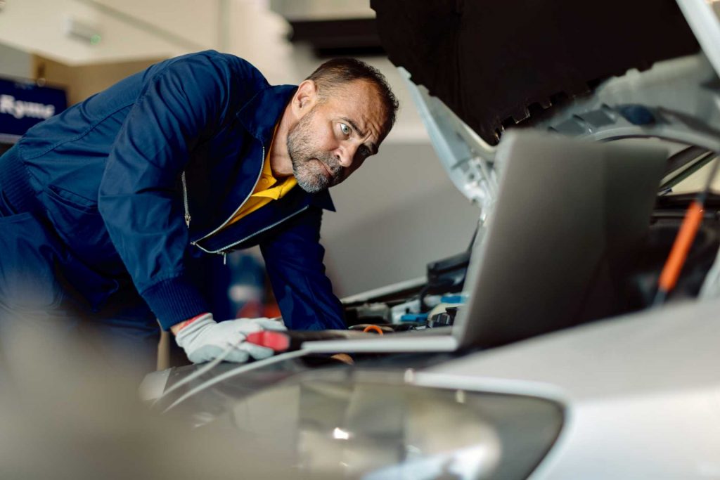 modern vehicle maintenance, technician hooking up computer to car